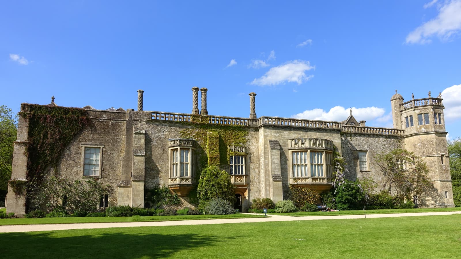 The south front of Lacock Abbey in sunlight, with lawns in front of it